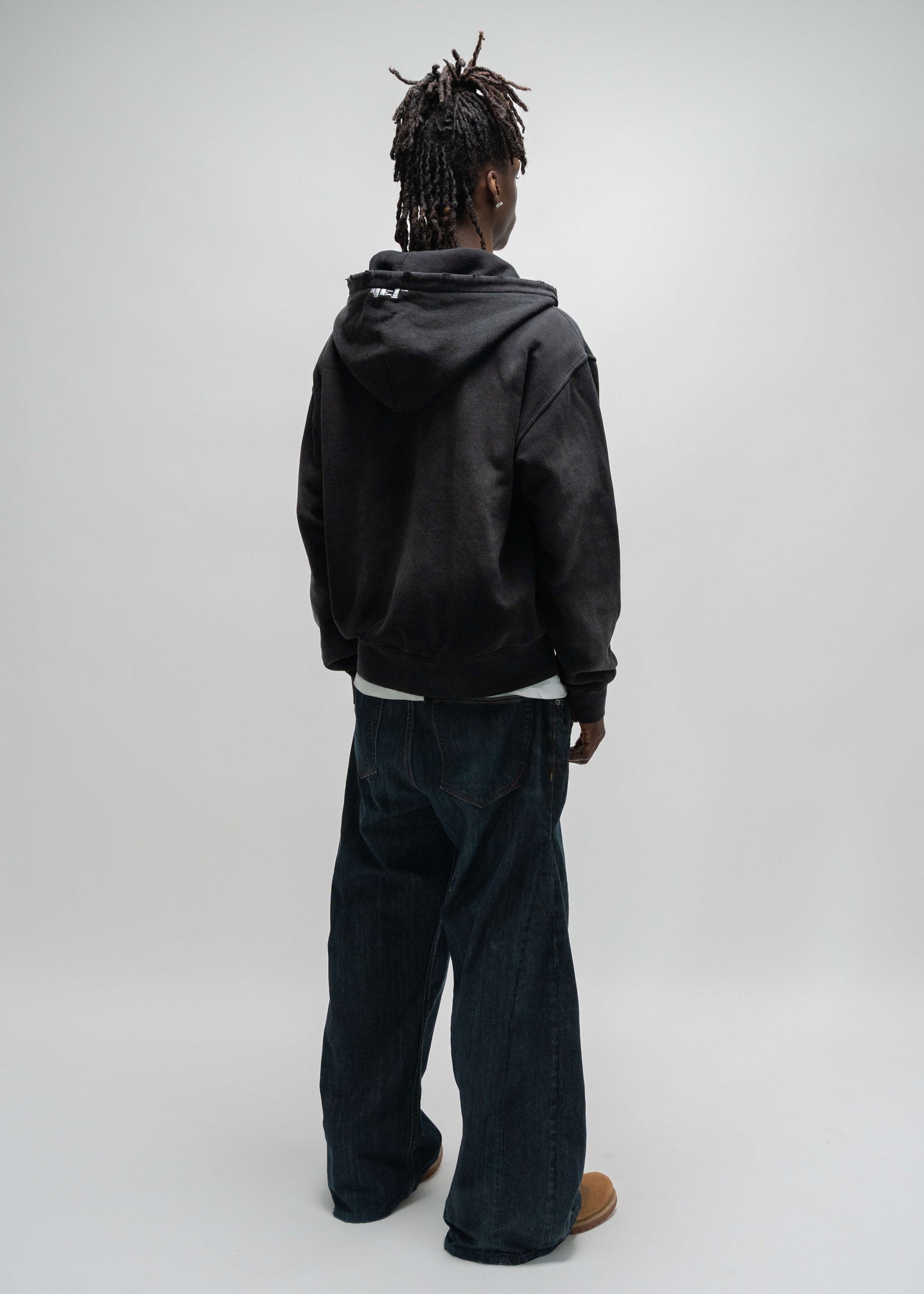 back view 45 degree angle of the model wearing the dogfight zip up by j3t. this is a full body shot compared to the previous picture. j3t hoodie