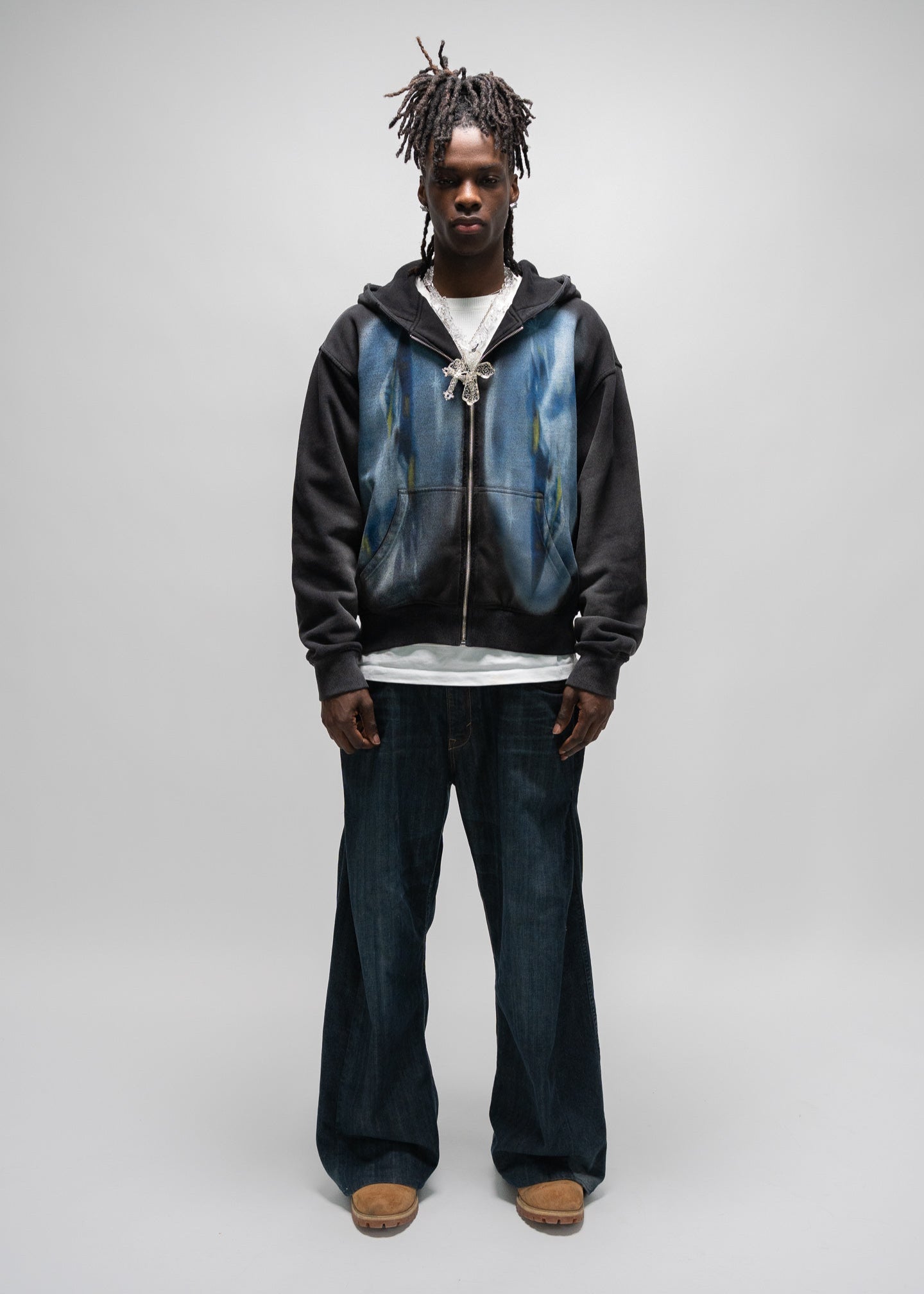 full body shot of the model wearing the dogfight zip up by j3t. his hands are down by his side. he has a white shirt underneath the zip up, paired with dark blue denim and wheat colored boots. j3t apparel