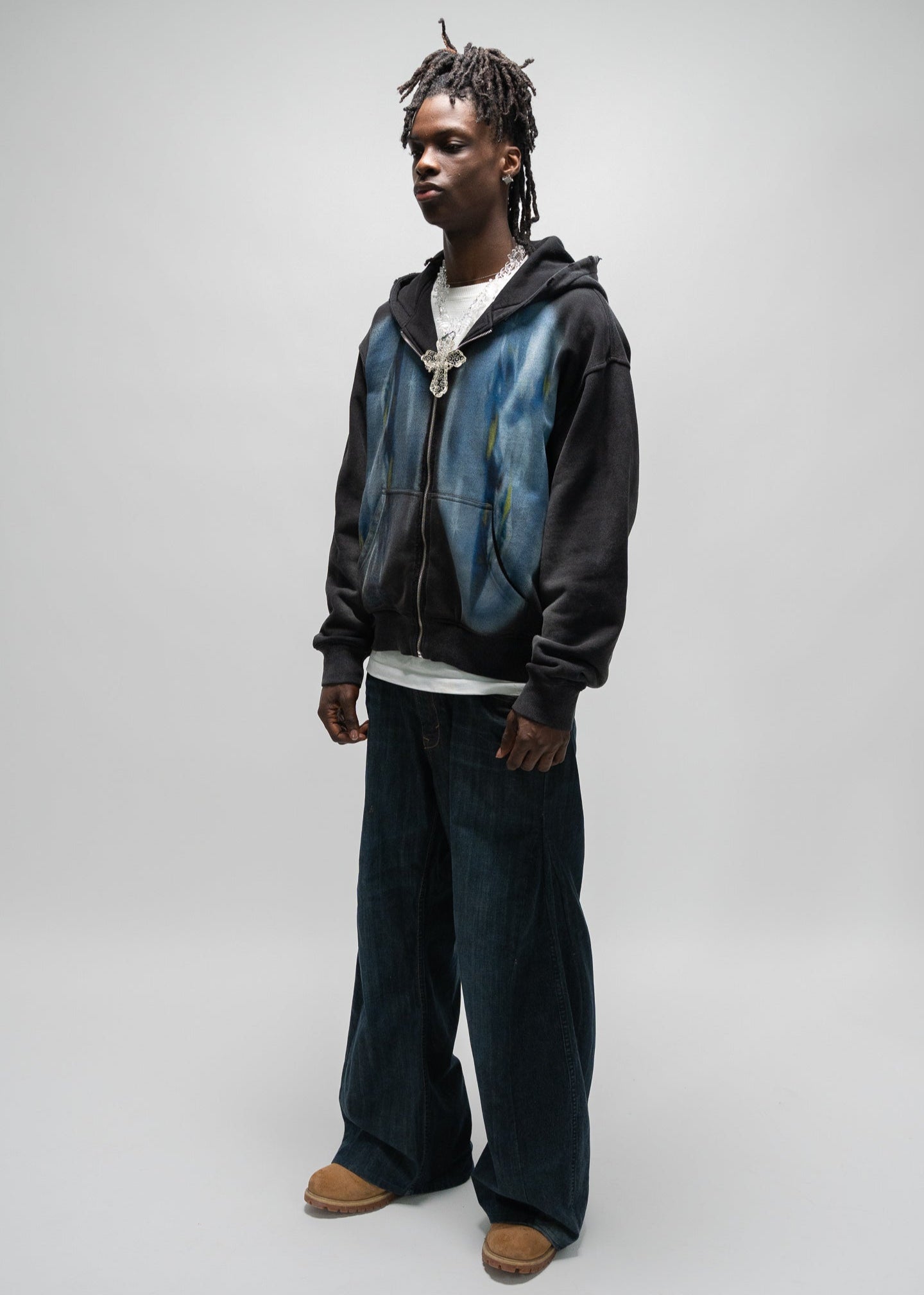 side view full body shot of the male model wearing the dogfight zip up by j3t. his body is angled at 45 degrees. his arms are down by his hips. J3T