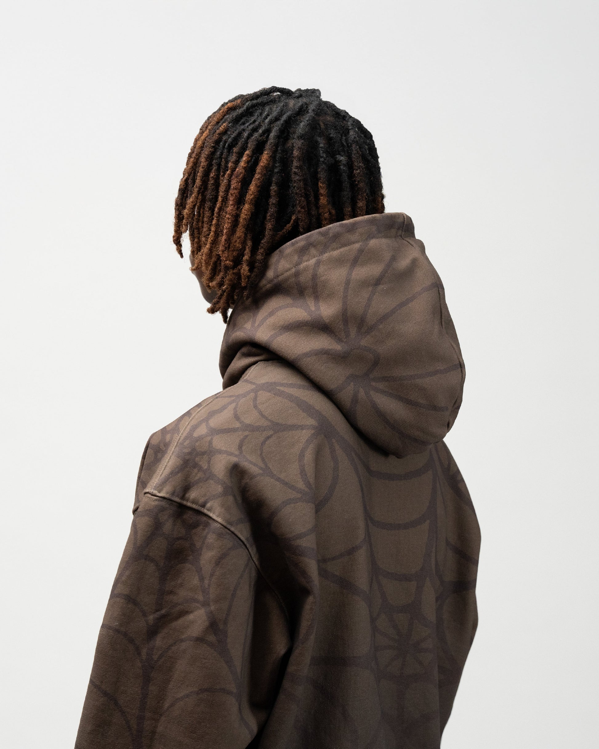 close up angle of the model at a 45 degree angle facing the back. it is showcasing the spider print on the hood. j3t apparel