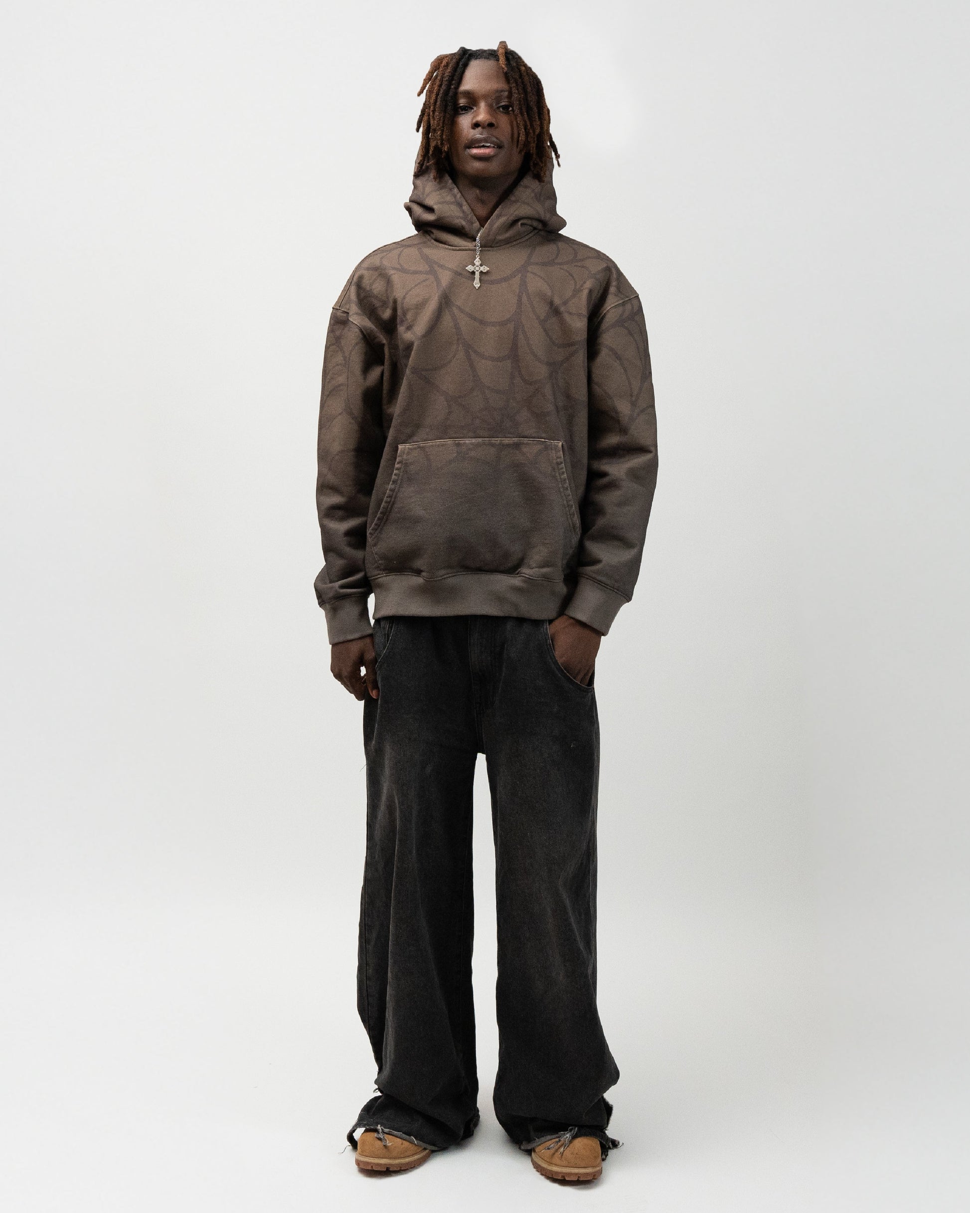 full body angle of the male model wearing the green spider hoodie. his right hand is in his pocket. j3t