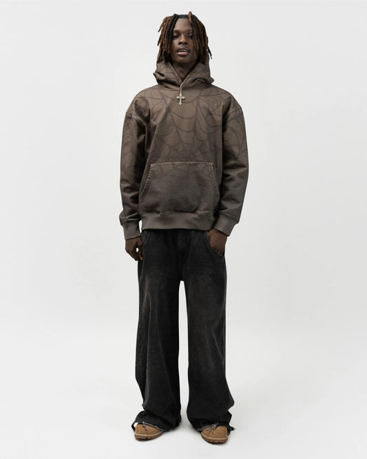 Full body angle of male model wearing the green spider hoodie by j3t. His right hand is in the pocket of his pants. j3t apparel