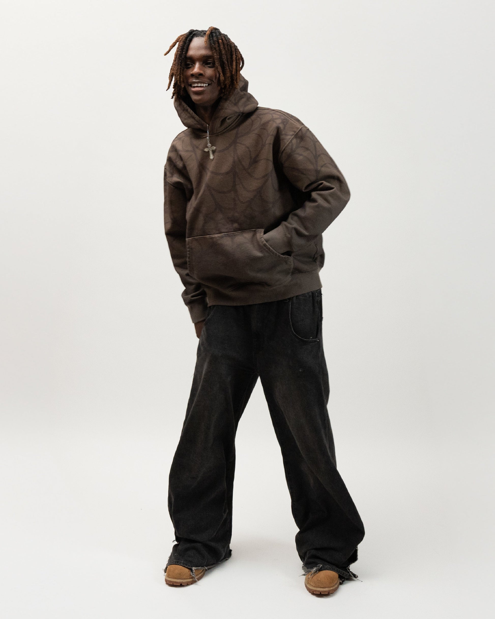 Model posing with his right hand in the hoodie pocket. he is smiling and leaning to the side. J3T APPAREL