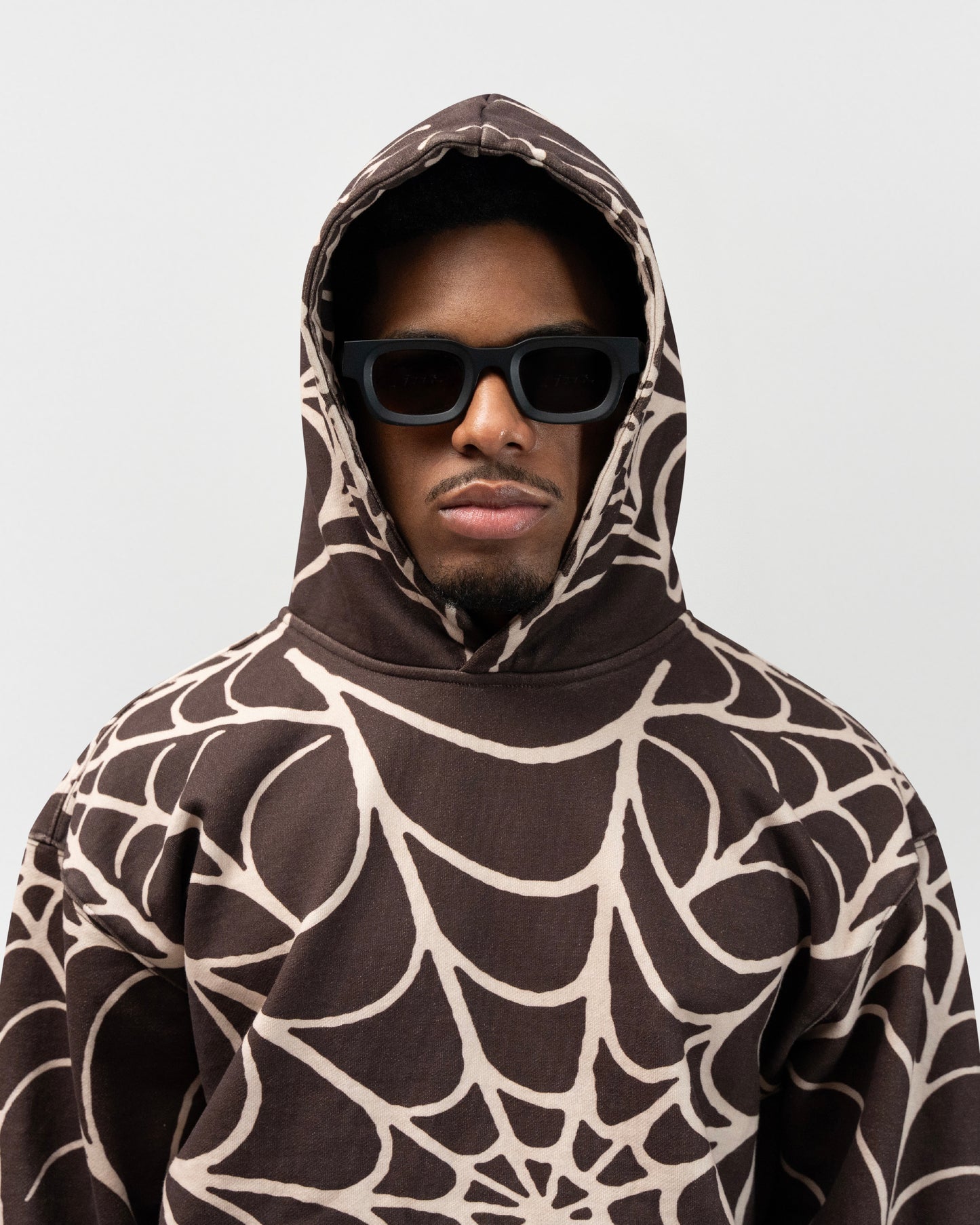 close up angle of male model wearing the brown spider hoodie by everythingj3t. It is a half body shot. jet