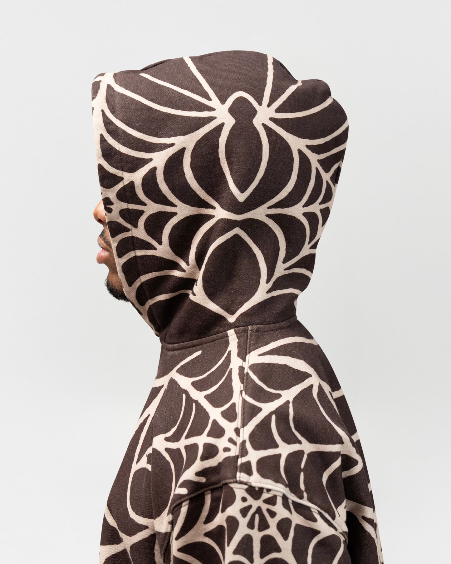 The model has the hood up. It is a close up shot showcasing the spider web details on the hood of the spider hoodie