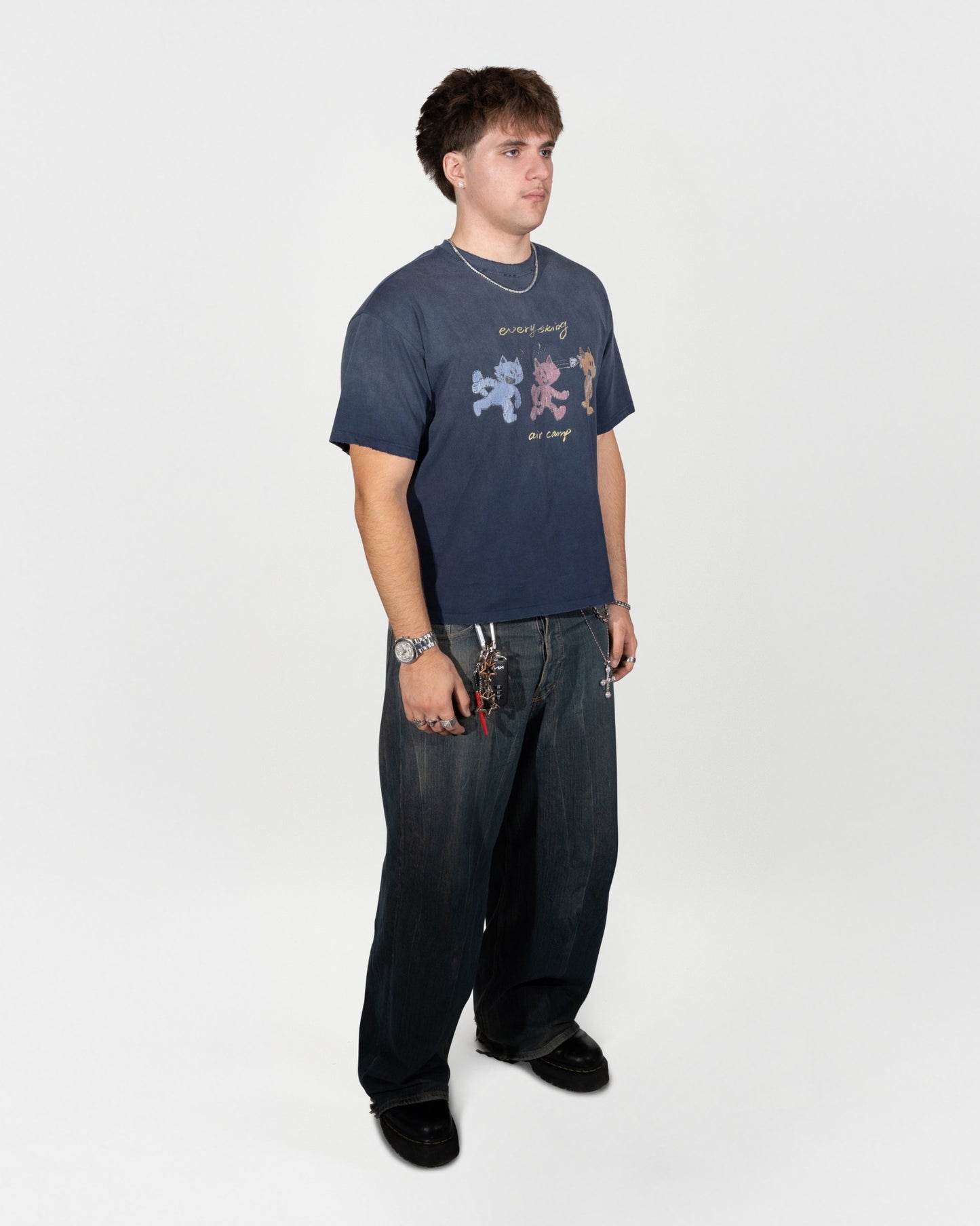 Full body front facing 45 degree angle. The model is styled wearing the air camp tee and greyish blue jeans, along with some accessories. J3T APPAREL