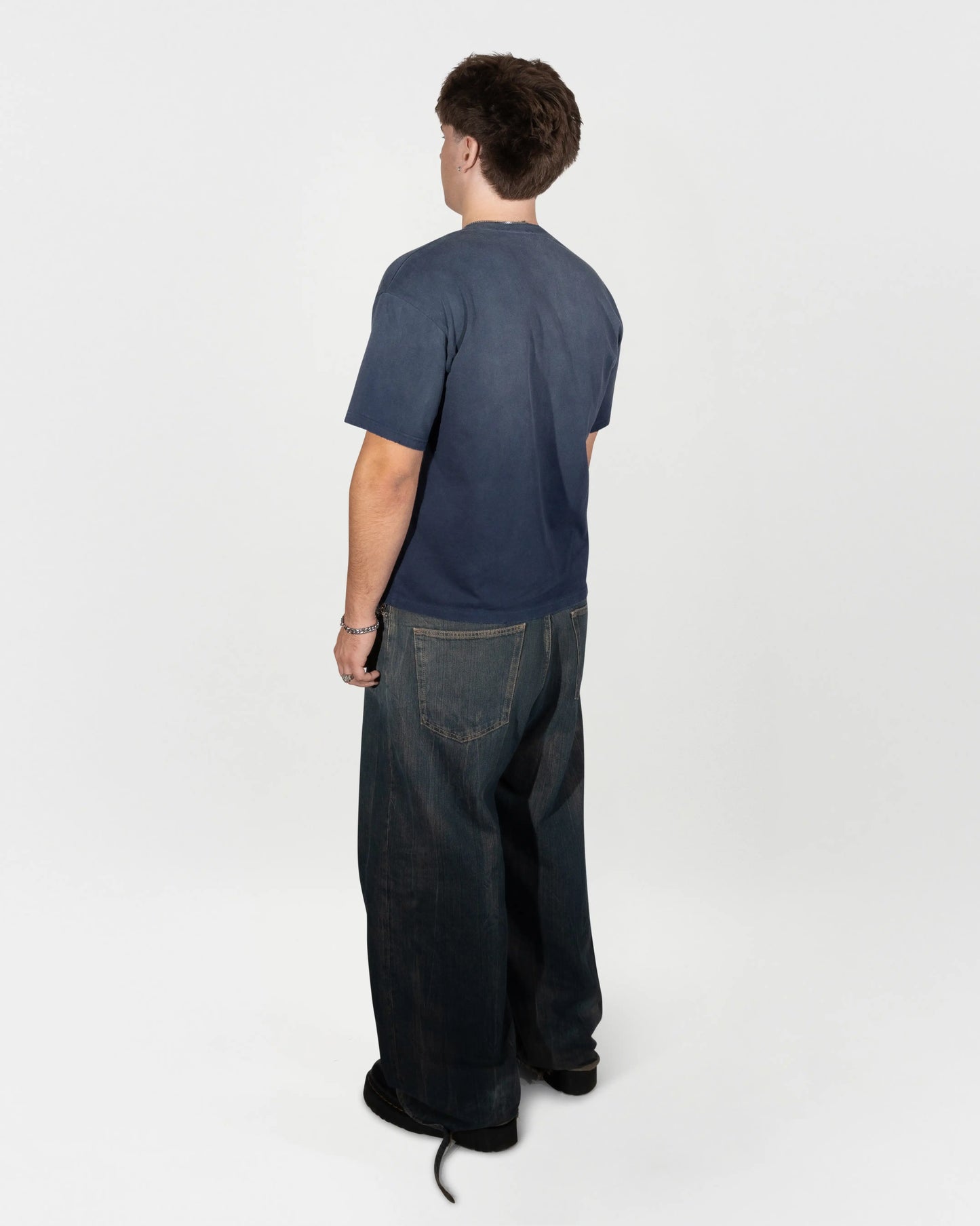 Full body back view of the model wearing the air camp tee by J3T. he is at a 45 degree angle. jet
