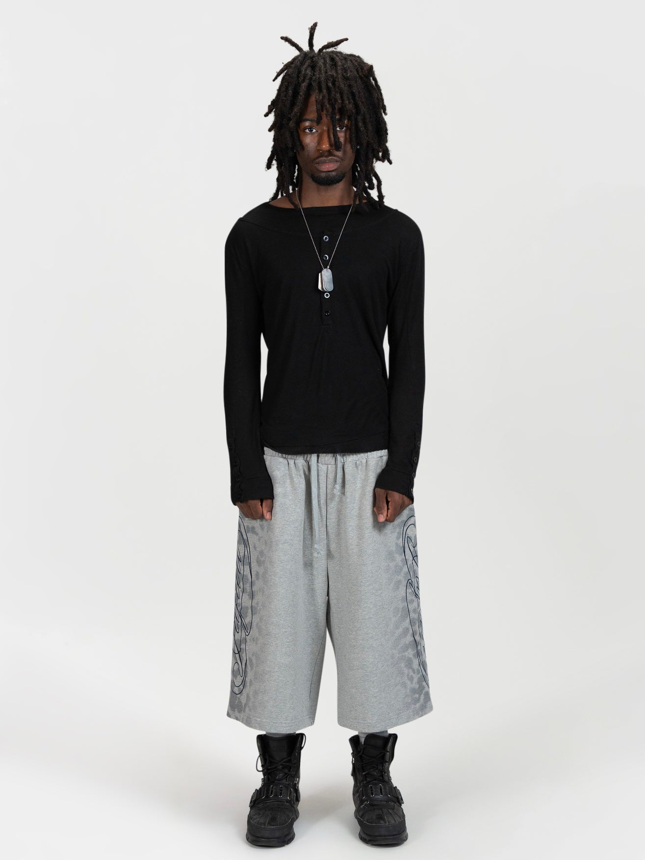 Front facing full body shot of a male model wearing the jafari shrorts by J3T. HE has on a black, long sleeve knit top , and black boots to complete the fit.