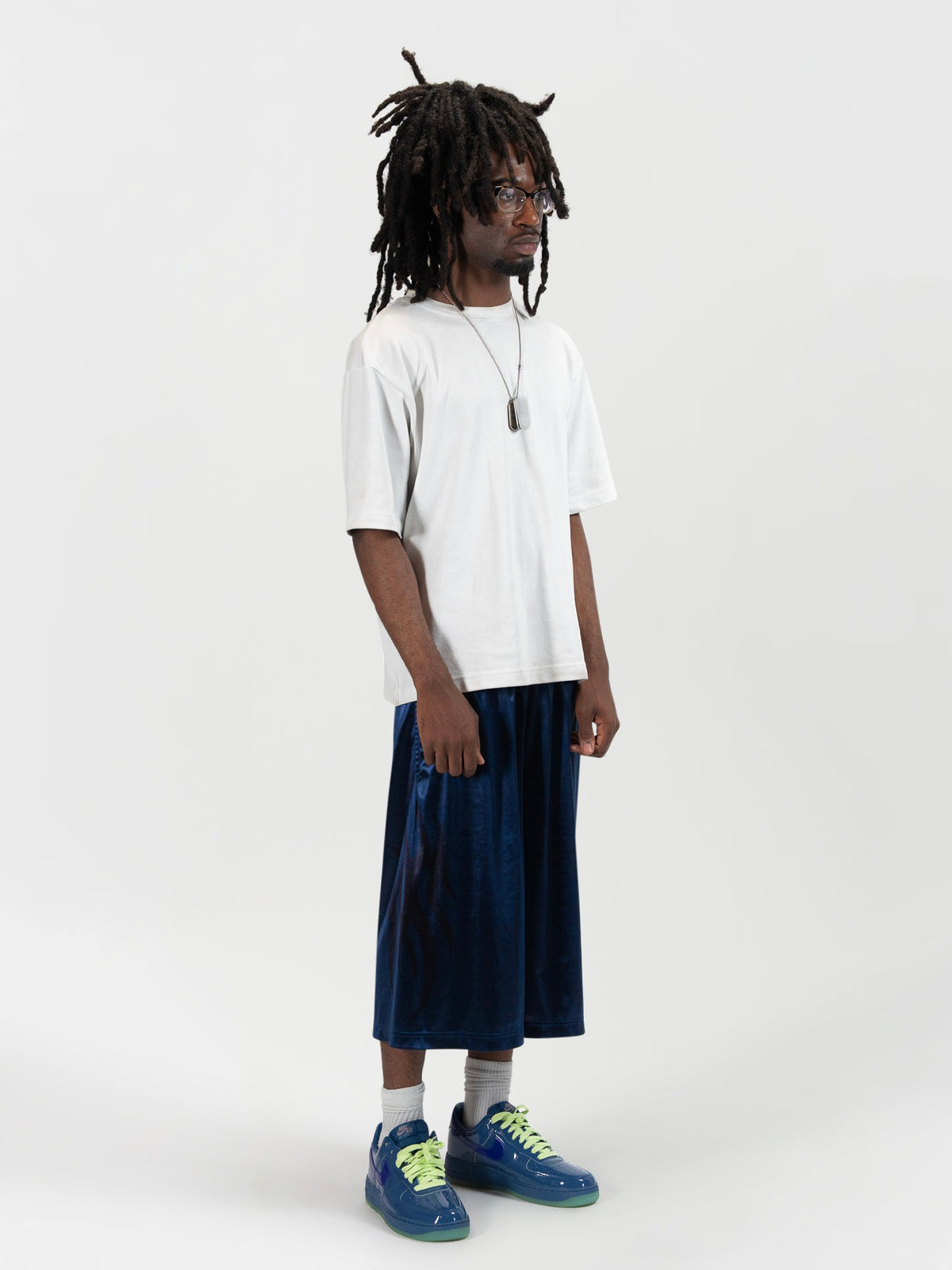right side 45 degree facing full body shot of a male model wearing the Tyson shrorts by J3T. HE has on a white shirt , and blue and yellow sneakers to complete the fit.