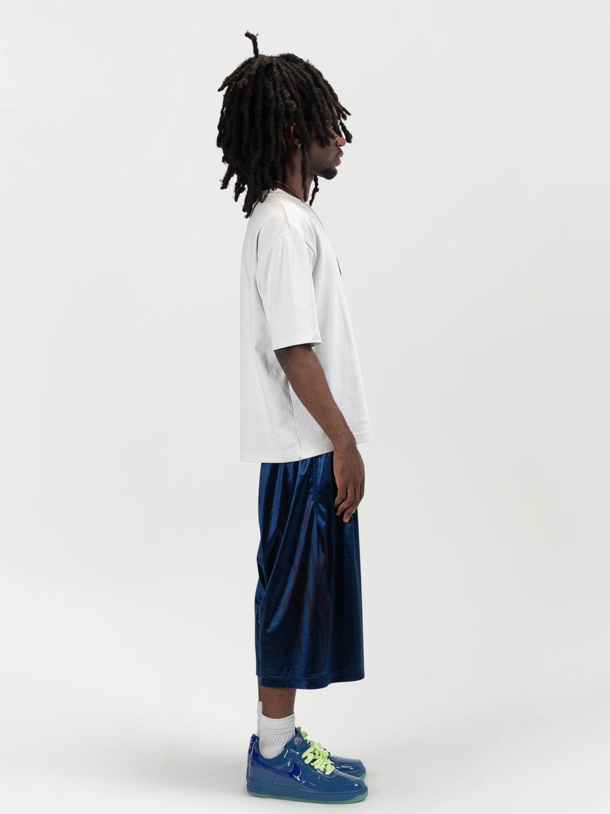 Side facing full body shot of a male model wearing the Tyson shrorts by J3T. HE has on a white shirt , and blue and yellow sneakers to complete the fit.