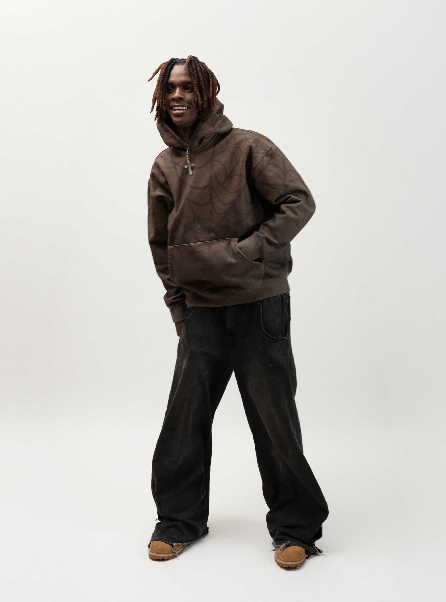 Model posing with his right hand in the hoodie pocket. he is smiling and leaning to the side. J3T APPAREL