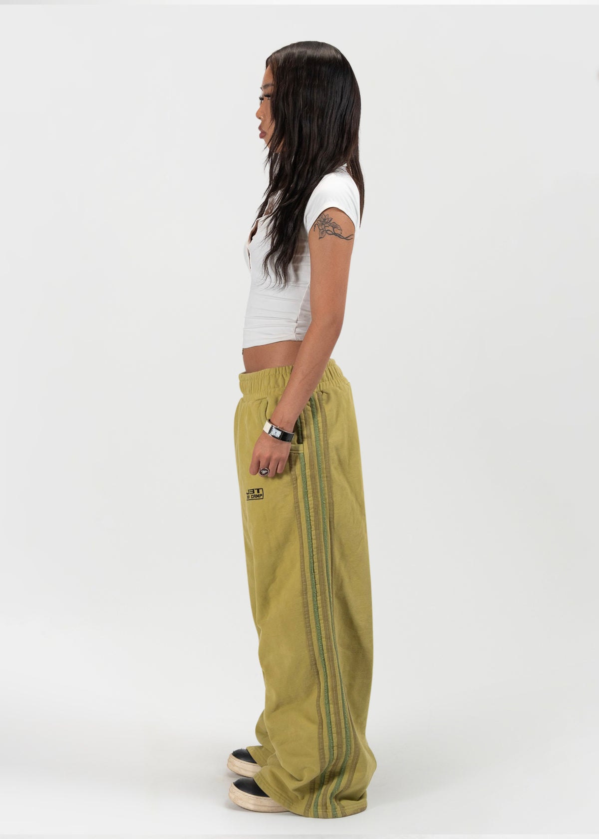 Side view facing female model shot of the model wearing the matcha sweats by J3T. She has on a white shirt to complete the fit