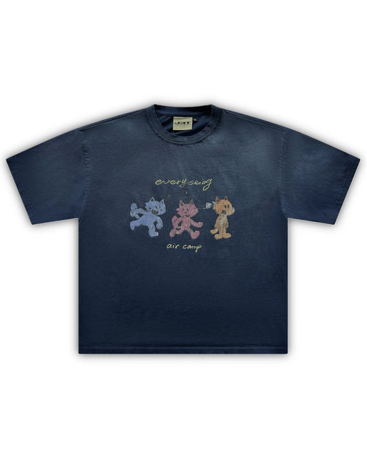 Flat lay image of the air camp tee by j3t. It is navy blue, featuring 3 wolf-like cartoon characters - blue, red and orange. above them is the text "everything". below them is the text "air camp"