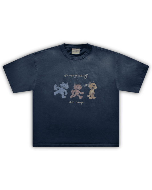 Flat lay image of the air camp tee by j3t. It is navy blue, featuring 3 wolf-like cartoon characters - blue, red and orange. above them is the text "everything". below them is the text "air camp"