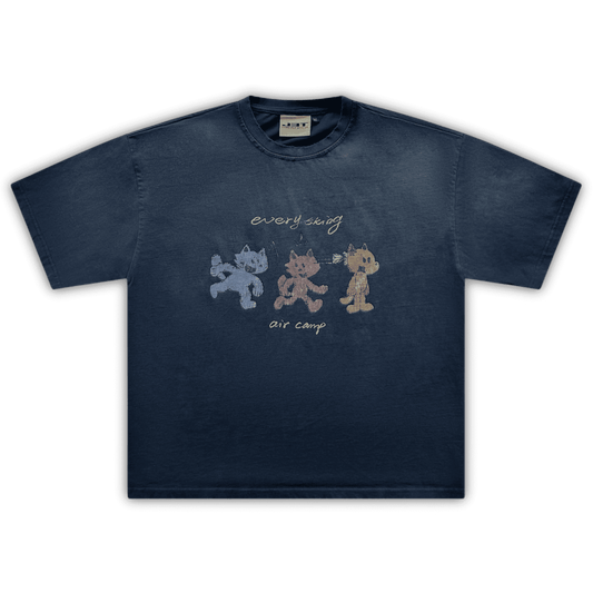 Flat lay image of the air camp tee by j3t. It is navy blue, featuring 3 wolf-like cartoon characters - blue, red and orange. above them is the text "everything". below them is the text "air camp"